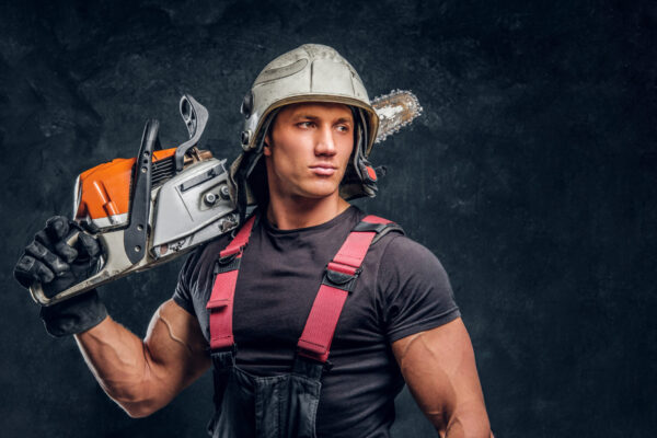 Lumberjack wearing protective clothes posing with a chainsaw